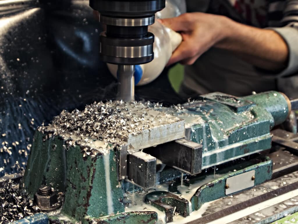 CNC milling process generating metal chips—highlighting one of the common sources of material waste in precision metal fabrication.